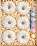 Six doughnut-shaped ceramics with paints and a brush